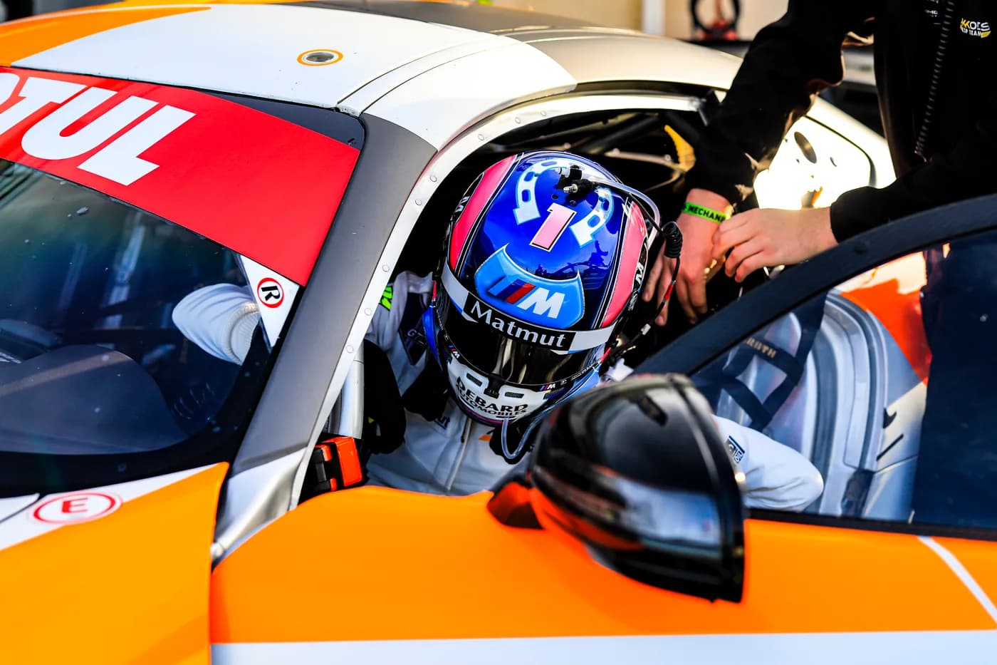 Carla au volant, casque et harnais, dans les stands